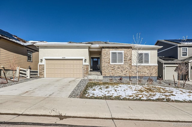 view of front of house with driveway, a garage, stone siding, fence, and stucco siding