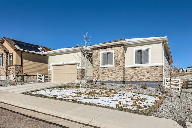 view of front facade featuring stone siding, an attached garage, concrete driveway, and stucco siding