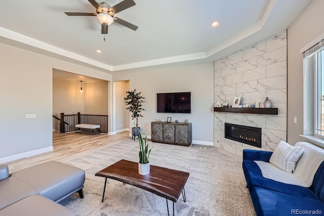 living room featuring recessed lighting, baseboards, a raised ceiling, and a high end fireplace