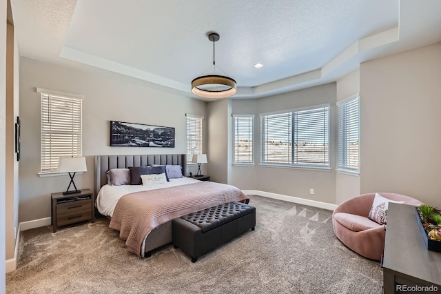 carpeted bedroom with baseboards, a raised ceiling, and a textured ceiling