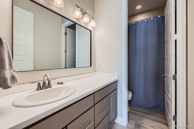 bathroom featuring curtained shower, vanity, toilet, and wood finished floors