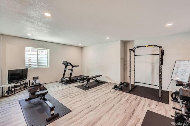 exercise room with a textured ceiling, wood finished floors, and recessed lighting