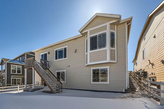 rear view of house with central air condition unit, fence, and stairway