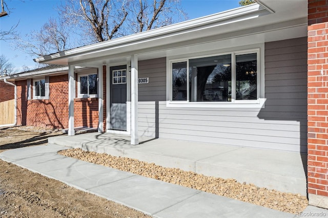 property entrance with covered porch and brick siding