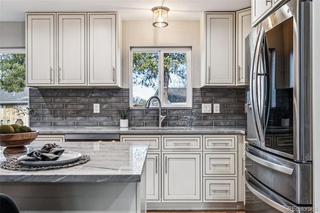 kitchen with backsplash, smart refrigerator, a sink, light stone countertops, and dishwasher