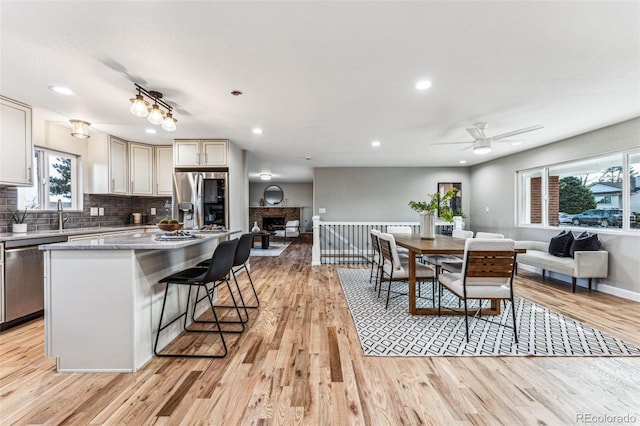 kitchen with stainless steel appliances, light wood-type flooring, open floor plan, and tasteful backsplash