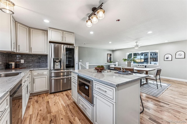 kitchen featuring light stone countertops, a kitchen bar, stainless steel refrigerator with ice dispenser, and dishwasher