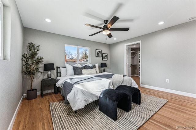 bedroom featuring recessed lighting, a spacious closet, baseboards, and wood finished floors