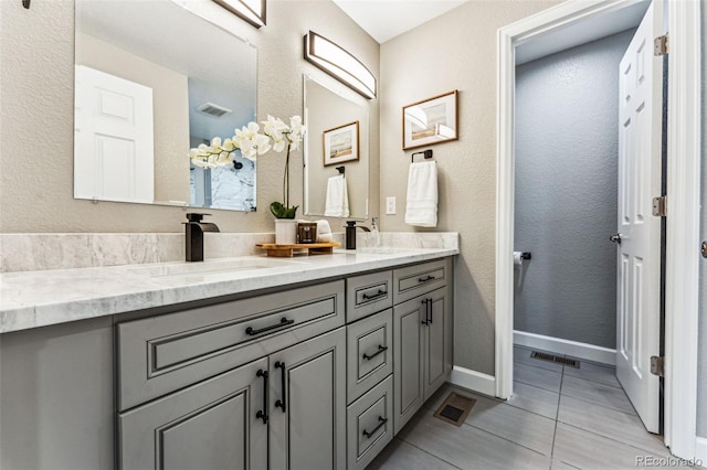 full bathroom featuring double vanity, baseboards, visible vents, tile patterned floors, and a sink