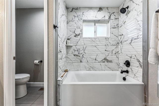 bathroom featuring a textured wall, toilet, baseboards, tub / shower combination, and tile patterned floors