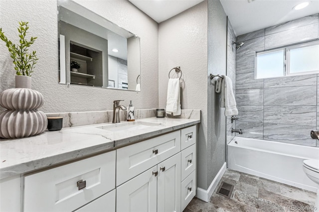 full bathroom featuring a textured wall, bathtub / shower combination, vanity, and stone finish flooring