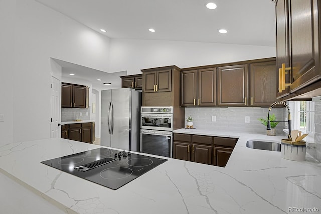 kitchen featuring stainless steel appliances, recessed lighting, lofted ceiling, tasteful backsplash, and a sink