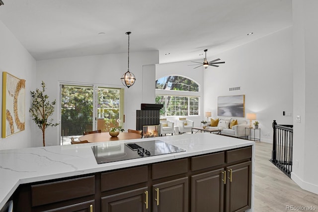kitchen featuring black electric stovetop, dark brown cabinetry, a ceiling fan, light wood finished floors, and high vaulted ceiling