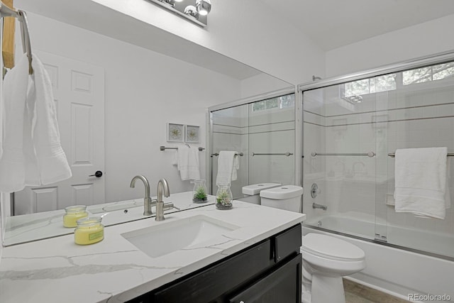 bathroom with toilet, vanity, and enclosed tub / shower combo