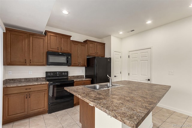 kitchen with black appliances, light tile patterned flooring, a center island with sink, and sink