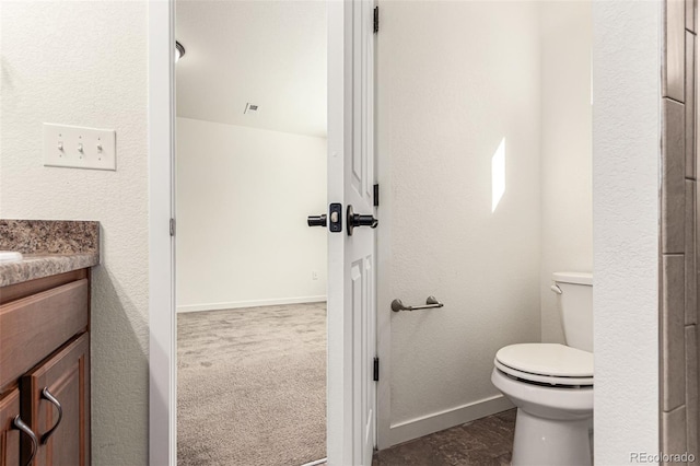 bathroom with lofted ceiling, toilet, and vanity