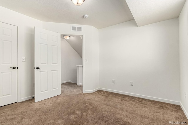 carpeted empty room with lofted ceiling