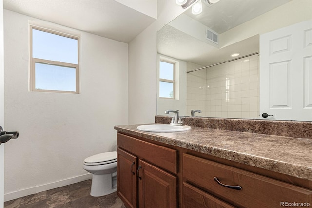 bathroom with vanity, toilet, and a tile shower