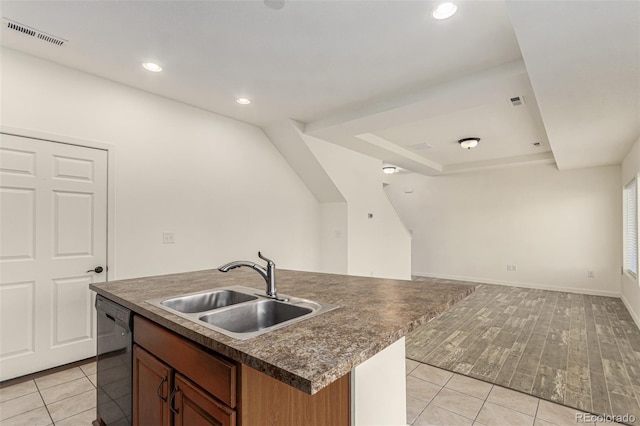 kitchen featuring dark countertops, visible vents, open floor plan, a sink, and dishwasher