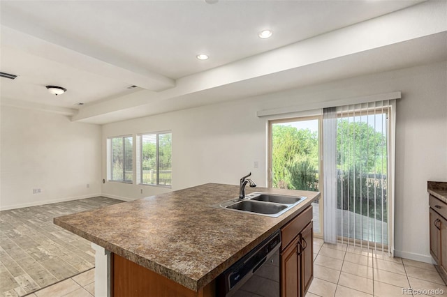 kitchen with black dishwasher, dark countertops, a sink, and baseboards