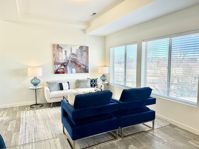 living area with baseboards, plenty of natural light, visible vents, and wood finished floors