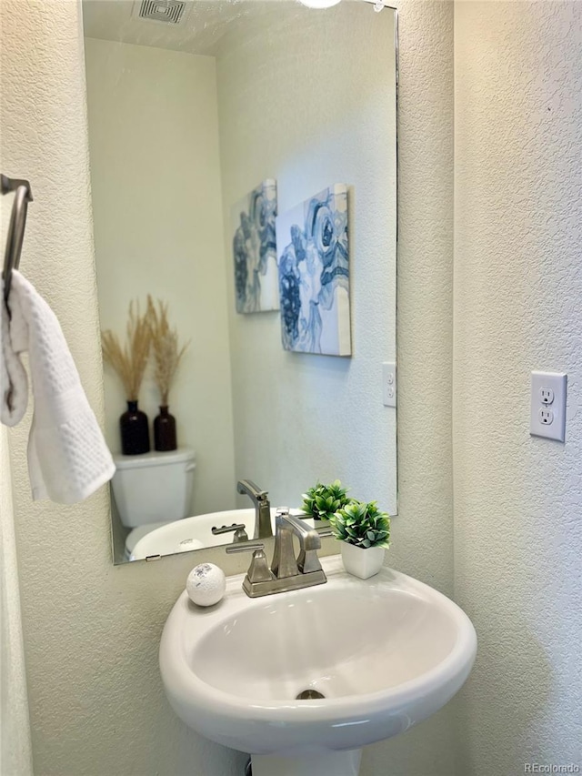 bathroom featuring a textured wall and a sink