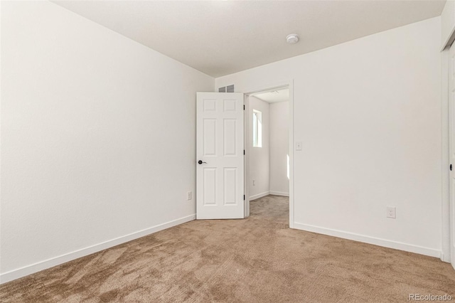 empty room featuring light colored carpet and baseboards