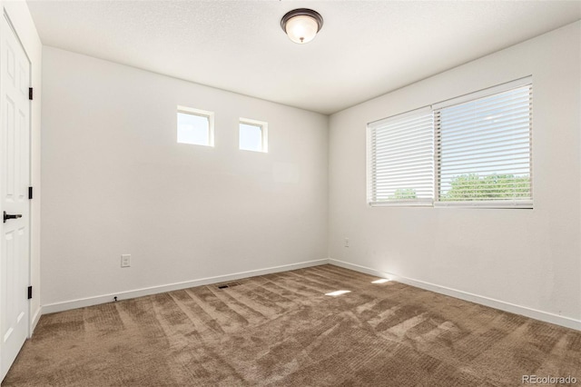 carpeted spare room featuring a textured ceiling and baseboards