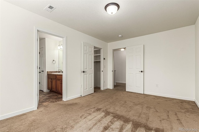 unfurnished bedroom with ensuite bathroom, carpet floors, visible vents, and baseboards