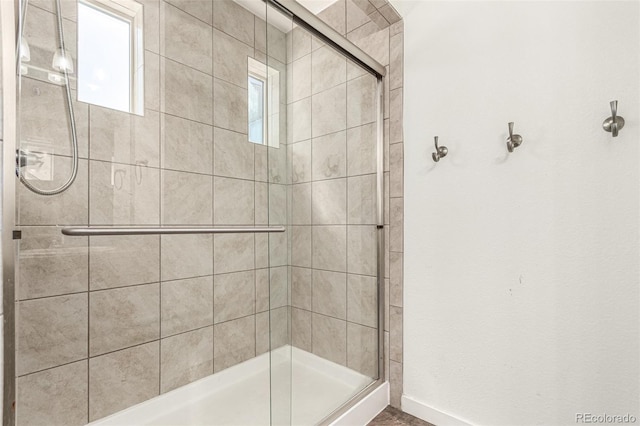 full bathroom featuring a stall shower and baseboards