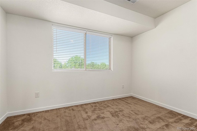 empty room featuring carpet, visible vents, a textured ceiling, and baseboards