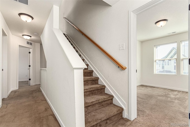 staircase with carpet floors, visible vents, and baseboards