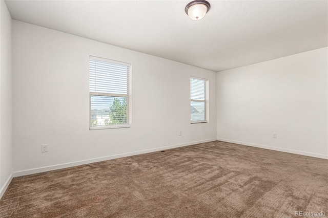 carpeted spare room with baseboards and a wealth of natural light