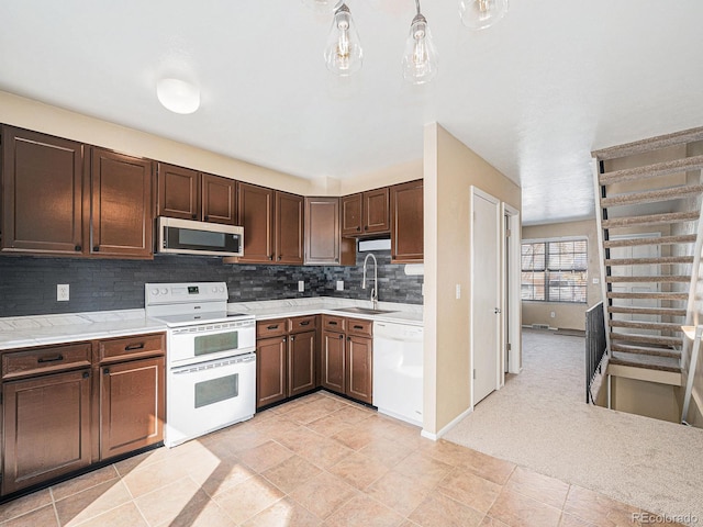 kitchen with dark brown cabinetry, sink, tasteful backsplash, hanging light fixtures, and white appliances