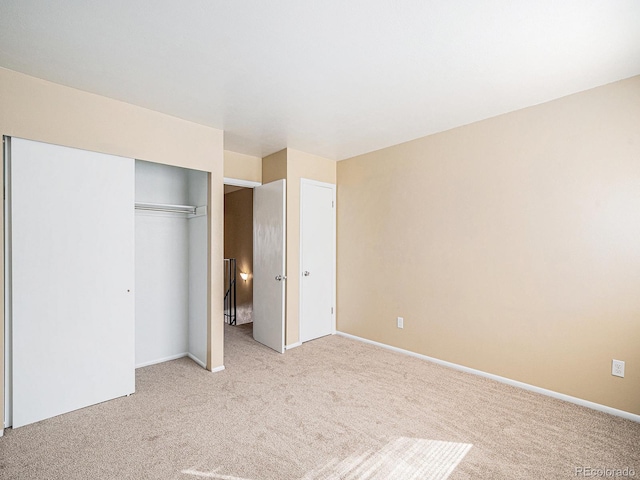 unfurnished bedroom featuring light carpet and a closet