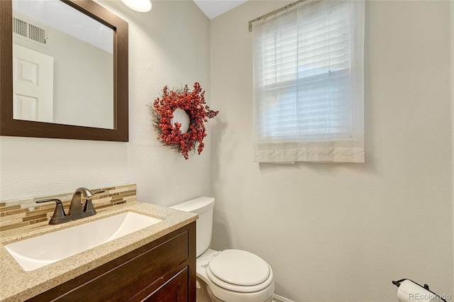 bathroom featuring vanity, tasteful backsplash, and toilet