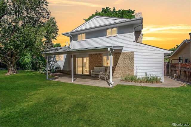 6584 S Clermont Ct, Centennial, CO 80121 - back of house at dusk with a patio area, a chimney, and brick siding