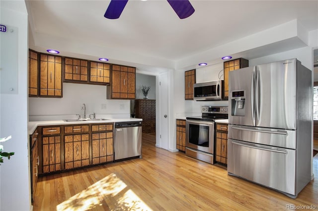 6584 S Clermont Ct, Centennial, CO 80121 - kitchen with appliances with stainless steel finishes, a ceiling fan, brown cabinetry, light wood-type flooring, and light countertops