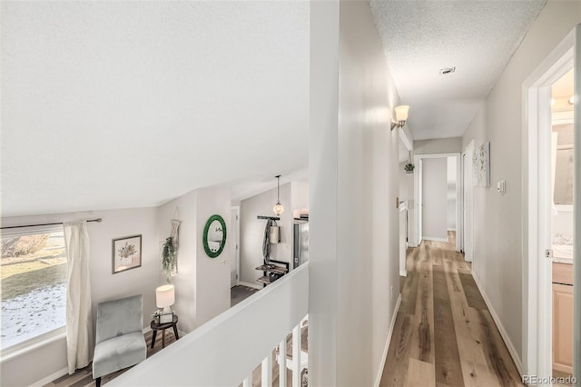 hallway with hardwood / wood-style floors and a textured ceiling