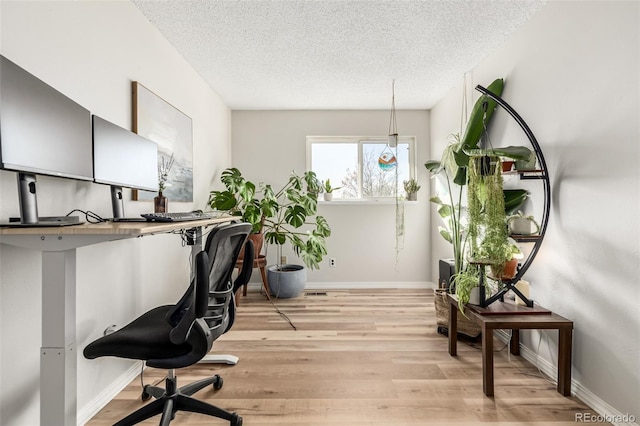 home office featuring a textured ceiling and light hardwood / wood-style flooring