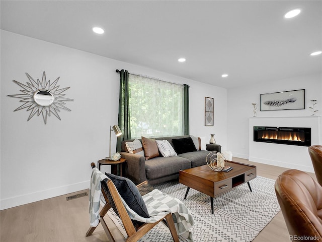 1517 S Elkhart St, Aurora, CO 80012 - living room featuring recessed lighting, light wood-type flooring, a glass covered fireplace, and baseboards