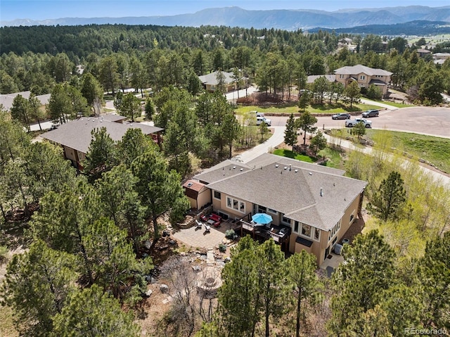aerial view of property and surrounding area featuring a heavily wooded area and a mountainous background