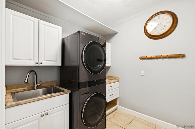 washroom featuring stacked washer / dryer, cabinet space, baseboards, and light tile patterned floors