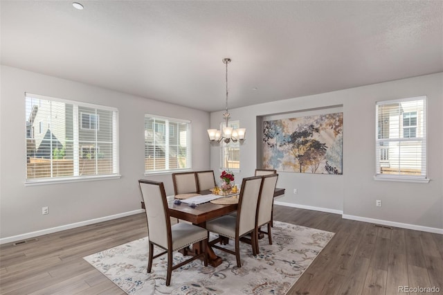 dining room featuring wood finished floors, a chandelier, and baseboards
