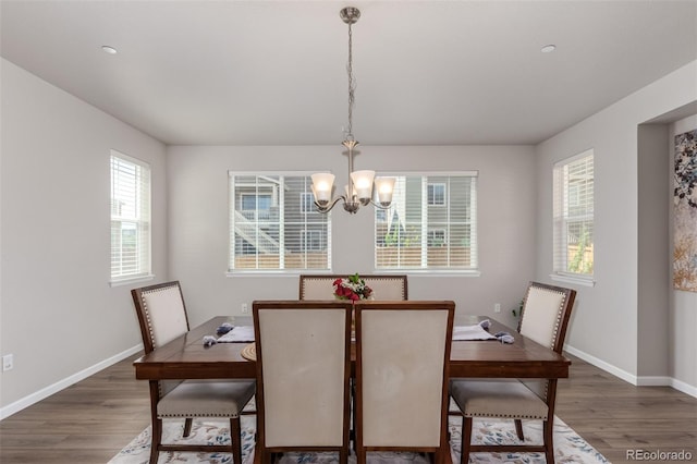 dining area featuring a chandelier, wood finished floors, and baseboards
