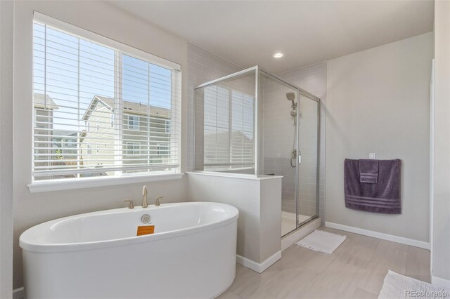 bathroom with a stall shower, a freestanding bath, baseboards, and recessed lighting