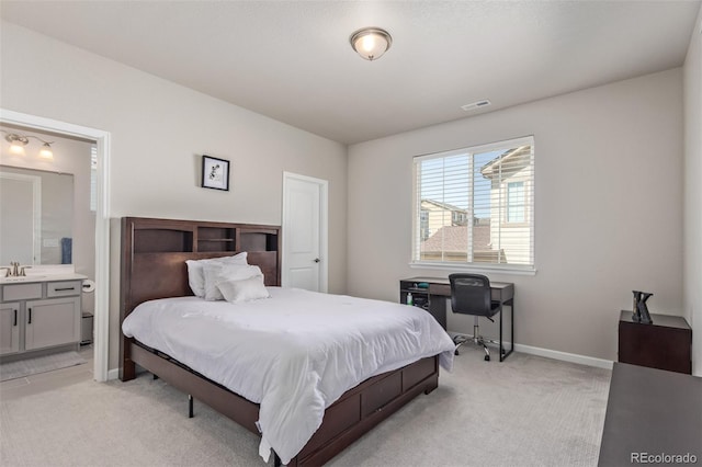 bedroom featuring light carpet, a sink, baseboards, and ensuite bathroom