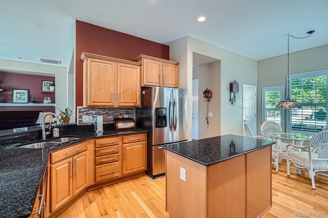 16644 Eolus Way, Broomfield, CO 80023 - kitchen featuring stainless steel refrigerator with ice dispenser, light wood finished floors, dark stone countertops, tasteful backsplash, and a center island