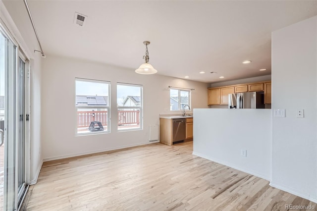 kitchen with light brown cabinets, light wood-type flooring, appliances with stainless steel finishes, and decorative light fixtures