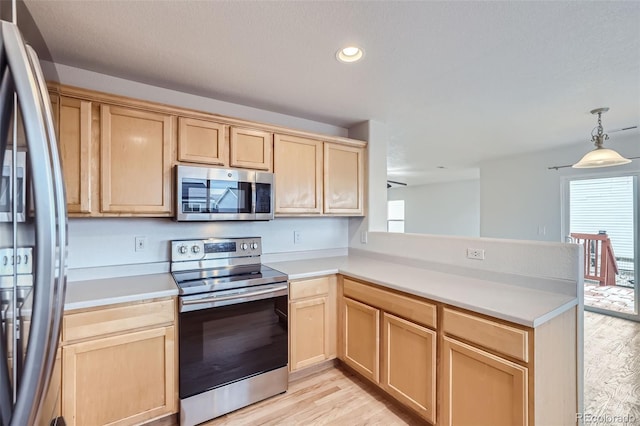 kitchen featuring kitchen peninsula, appliances with stainless steel finishes, hanging light fixtures, and plenty of natural light